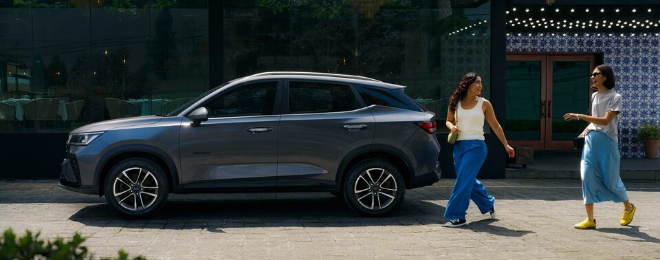 Two Happy Women Walk Past a Grey 2026 Chevrolet Groove Parked Next to a Building