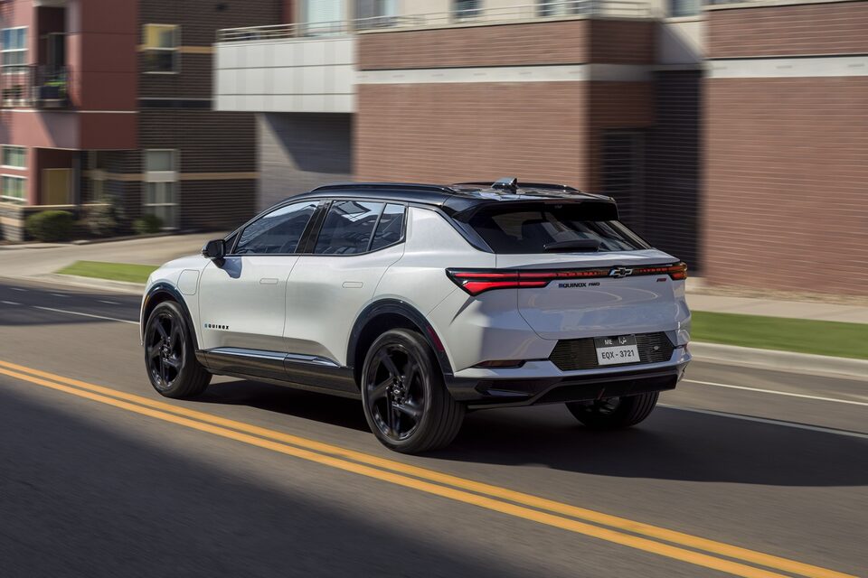 Rear three-quarters view of 2025 Equinox EV on road surrounded by buildings
