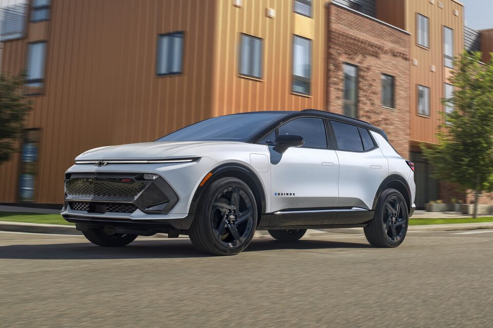 Rear three-quarters view of 2025 Equinox EV on road surrounded by buildings