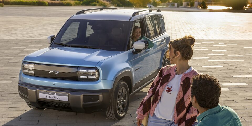 Chevrolet Spark EUV in Sea Blue with Polar White roof parked outdoor, with a woman and man in the foreground looking toward the vehicle.
