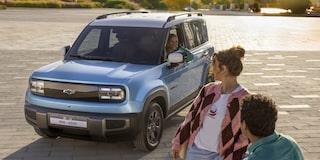 Chevrolet Spark EUV in Sea Blue with Polar White roof parked outdoor, with a woman and man in the foreground looking toward the vehicle.