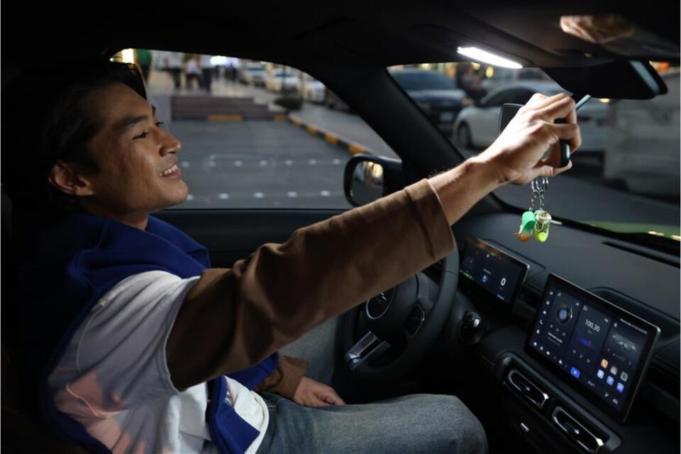 Driver smiling while adjusting the rearview mirror inside the Chevrolet Spark EUV.