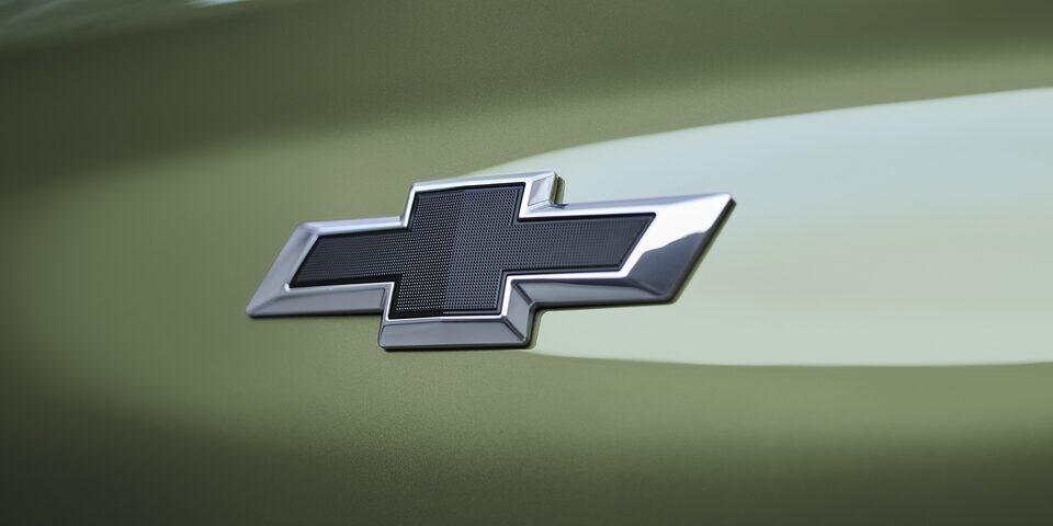 Side view of a man using a charging port on a Khaki Green 2026 Chevrolet Captiva PHEV