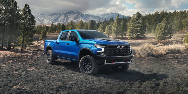 The 2024 Silverado Parked in a Grass Field with a Gorgeous Mountain Backdrop