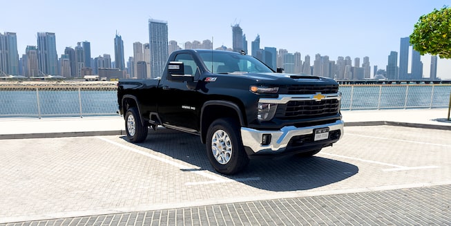 Black Chevy Silverado HD Towing Cargo on A Scenic Road