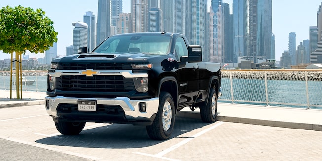 Black Chevy Silverado HD Towing Numerous Round Bales of Hay on a Farm