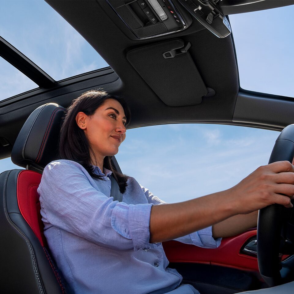 Side View of a Woman Driving a 2025 Chevy Equinox EV under a Blue Sky