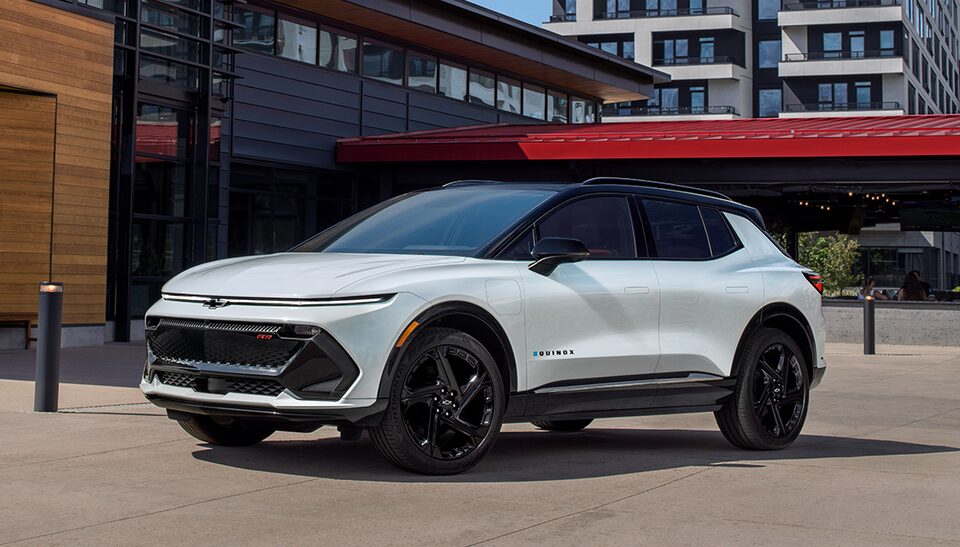 Front Three Quarters of a White 2025 Equinox EV Next to a Building
