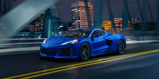 Three Quarters View of a 2025 Blue Chevy Corvette Driving Down the Bridge at Night
