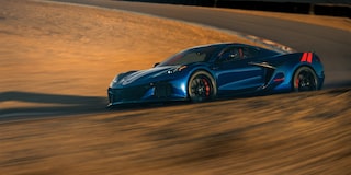 A Blue Chevrolet Corvette Grand Sport Kicks Up Dust While Sliding Across a Sunlit Sand‑Covered Track Surface.