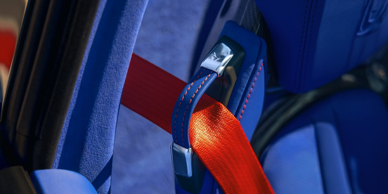 A Close‑Up View Shows a Bright Red Seatbelt Buckle Secured Against the Blue Leather Seat of a Chevrolet Corvette Grand Sport.