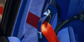 A Close‑Up View Shows a Bright Red Seatbelt Buckle Secured Against the Blue Leather Seat of a Chevrolet Corvette Grand Sport.