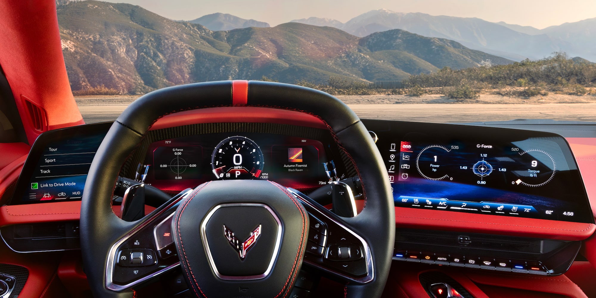 The Driver’s View Inside a Chevrolet Corvette Grand Sport Shows the Steering Wheel, Digital Displays, and a Mountain Landscape Visible Through the Windshield.