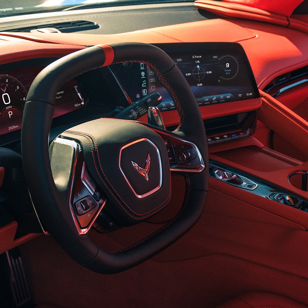 The Red Interior of a Chevrolet Corvette Grand Sport Features a Driver‑Focused Cockpit With a Flat‑Bottom Steering Wheel, Digital Gauge Cluster, and Angular Dashboard Layout.