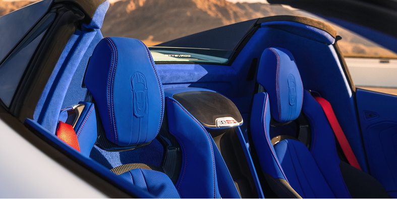 The Blue Leather Seats of a Chevrolet Corvette Grand Sport Convertible Are Shown in Bright Sunlight With Mountains Visible in the Background.