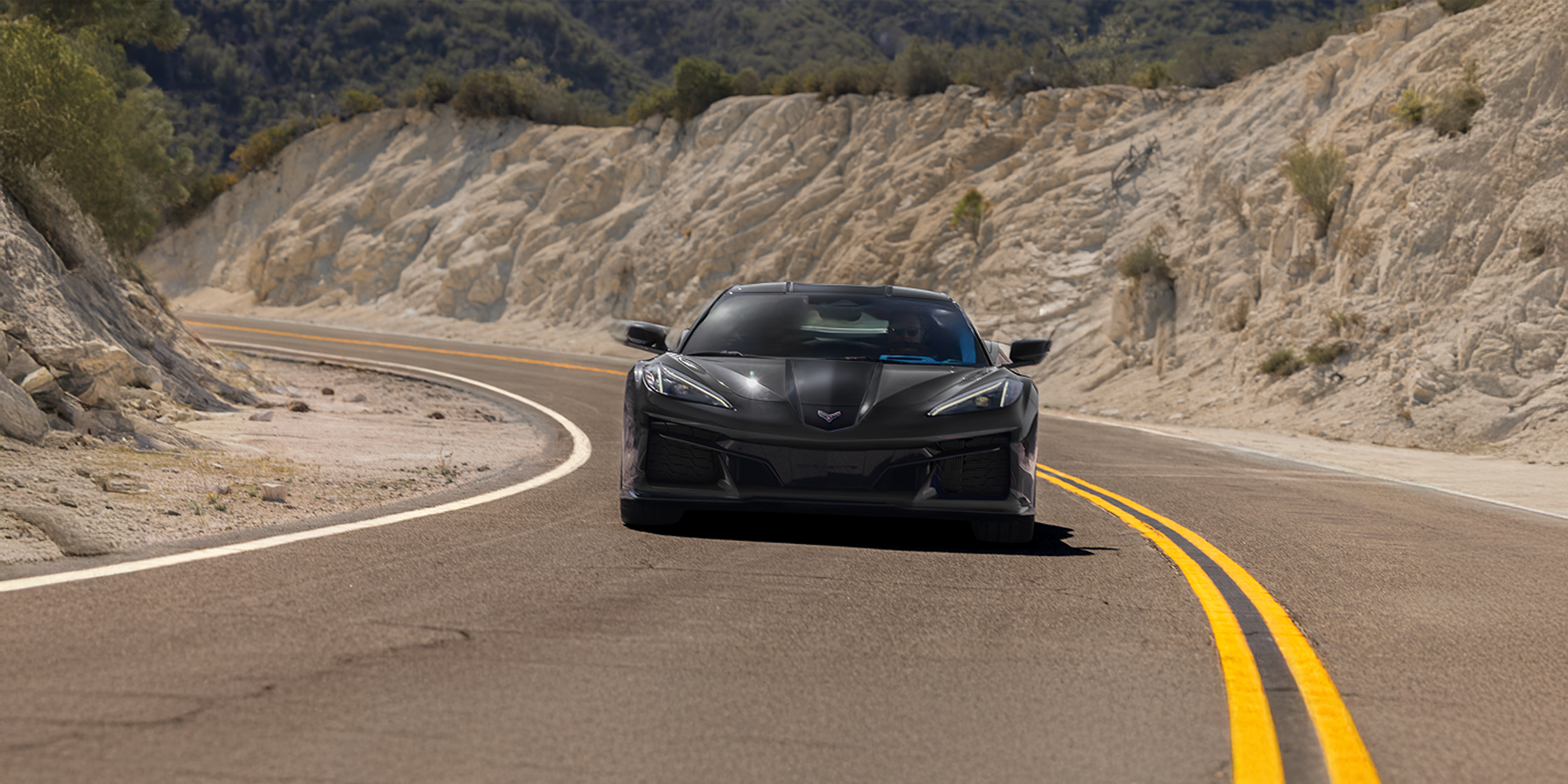 Front View of a Black Chevrolet Corvette Grand Sport Driving the Curve of a Mountain Road