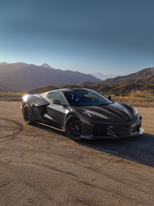 The Sun Shining on a Black Chevrolet Corvette Grand Sport X Parked on a Desert Mountain Overlook with Rugged Hills