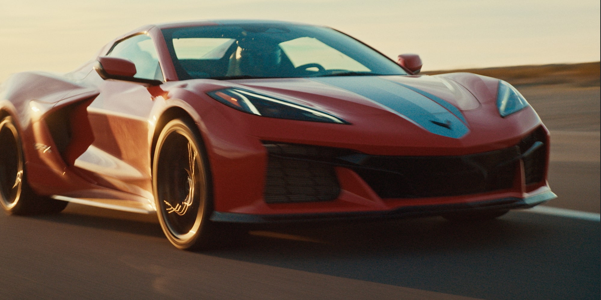 A Red Chevrolet Corvette Grand Sport Speeds Down a Sunlit Road