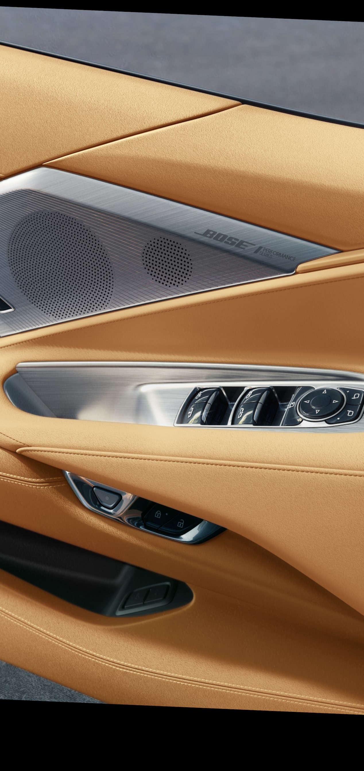 Primer plano del panel del interior de la puerta de un Chevrolet Corvette Z06 2027 de piel en Tostado con controles plateados y una bocina Bose