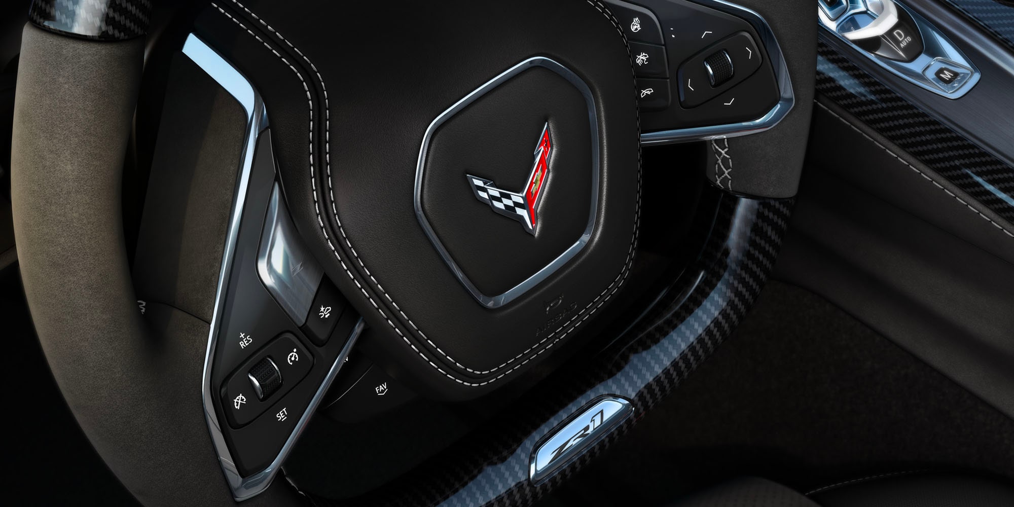 Un primer plano de la consola central de un Chevrolet Corvette Grand Sport donde se observan los controles de interruptores metálicos junto al juego de dos portavasos circulares en un modelo con el interior rojo.