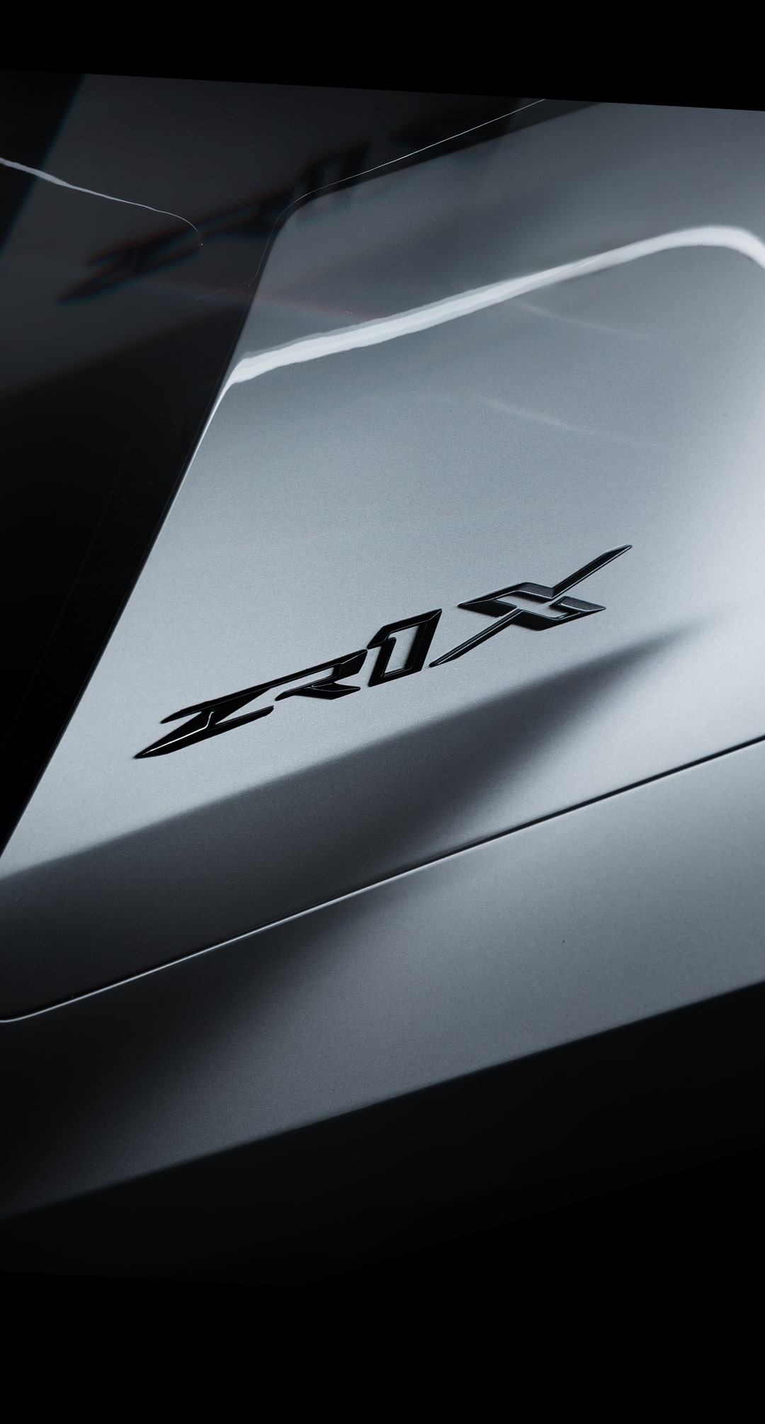 A Close-Up of the ZR1X Badge on the Rear Body Panel of a Silver Chevy Corvette ZR1X with Sharp Body Lines and Subtle Studio Lighting.
