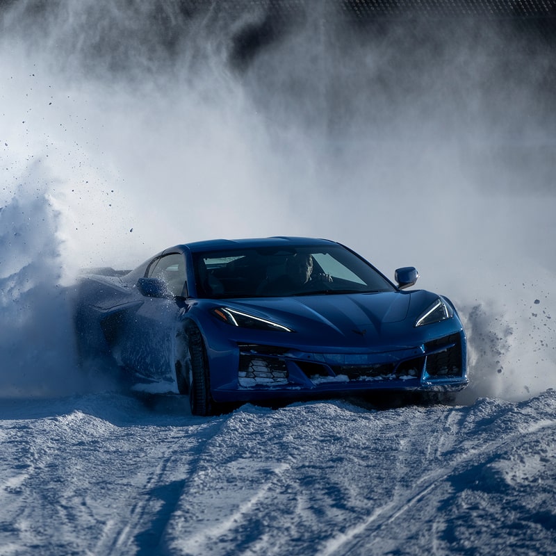 Front View of a Blue Chevy Corvette Stingray Driving Through Snow