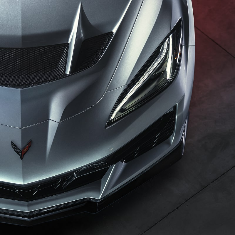 A Top View of the Front Corner and Hood of a Silver Chevrolet Corvette ZR1X Parked On Dark Grey Pavement
