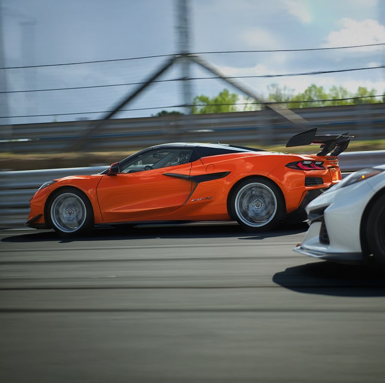 Profile View of a Red Chevy Corvette Speeding Down a Track Ahead of a Competitor