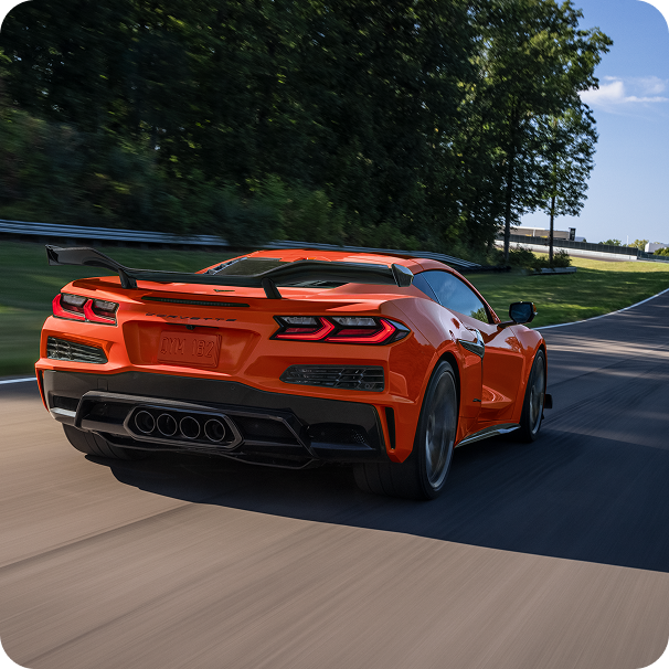 Rear View of a Red Chevy Corvette Z06 Driving Down a Road Lined with Trees