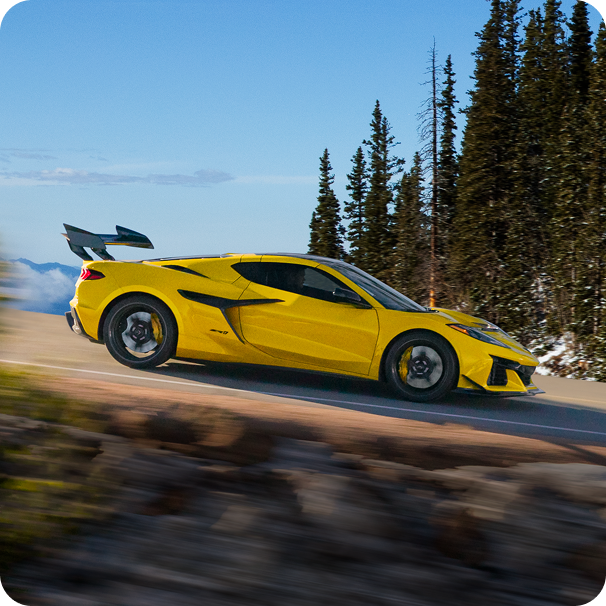 Profile View of a Yellow Chevy Corvette ZR1 Driving Down a Dirt Road Lined with Trees
