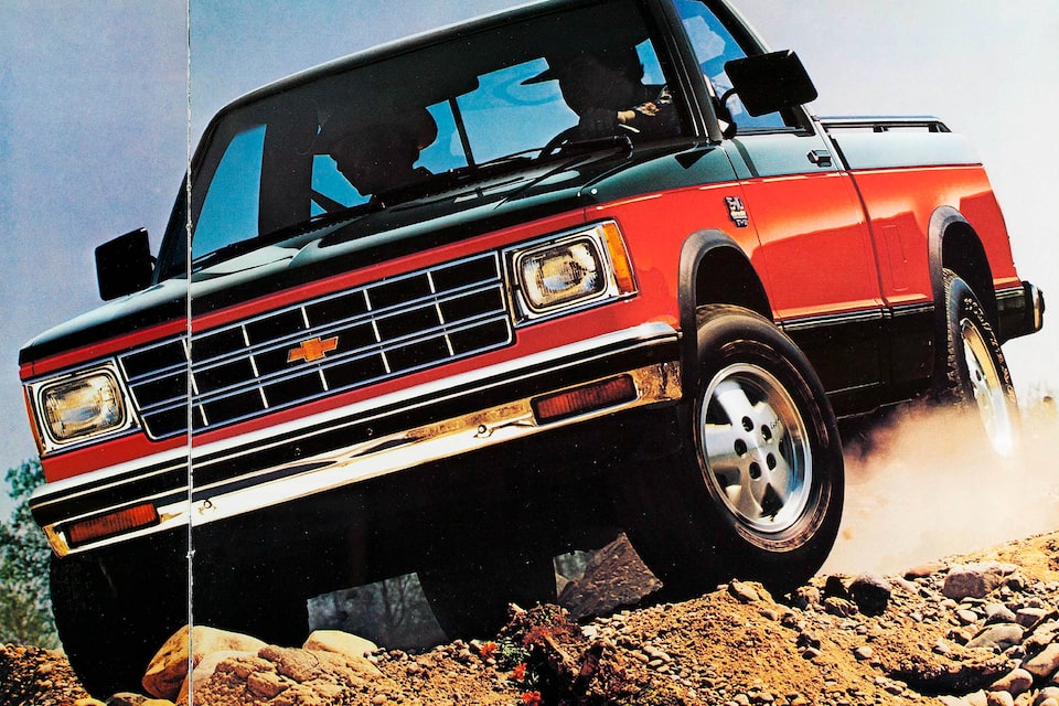 Una pickup Chevy S-10 de 1983 a dos tonos en rojo y negro transita un terreno accidentado en una foto del folleto de 1983.
