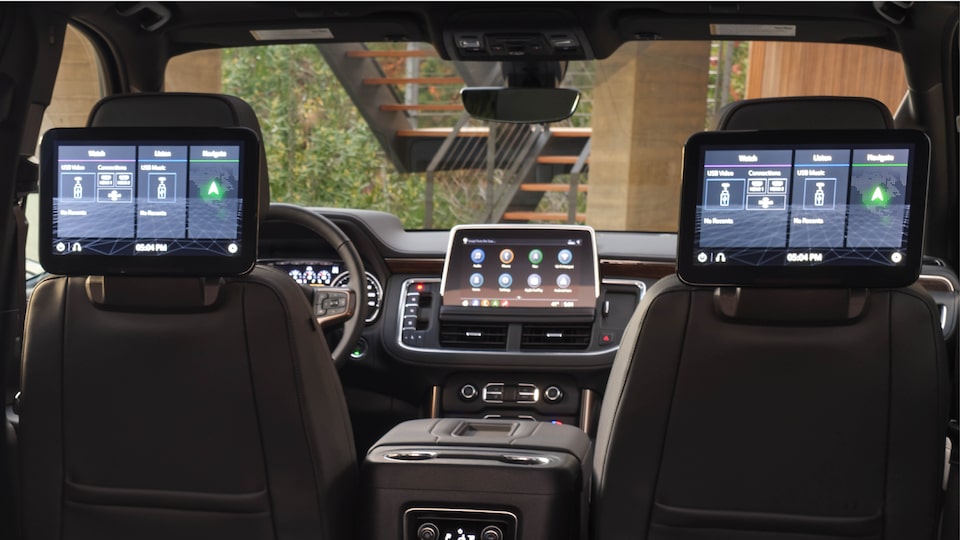 The interior of a 2021 Chevy Tahoe from the backseat, showing dual screens on the back of the frontseat headrests.