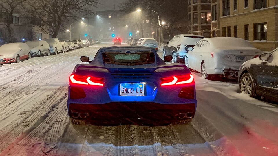 A bright blue Corvette is seen from the rear on a snowy street in Chicago.