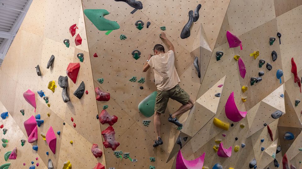 Ken Kuevibulvanich climbs a wall in a rock climbing gym.
