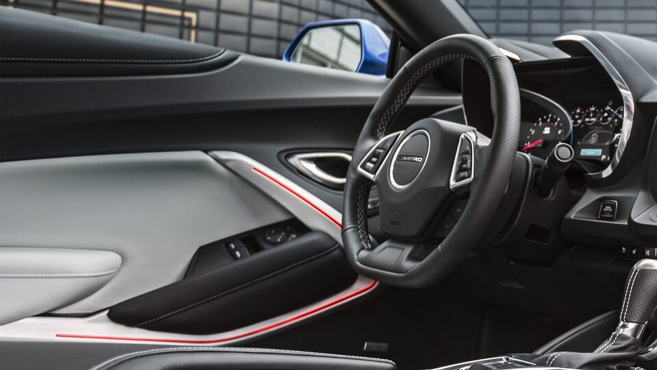 El volante y el ribete de la puerta iluminados adentro de un Camaro