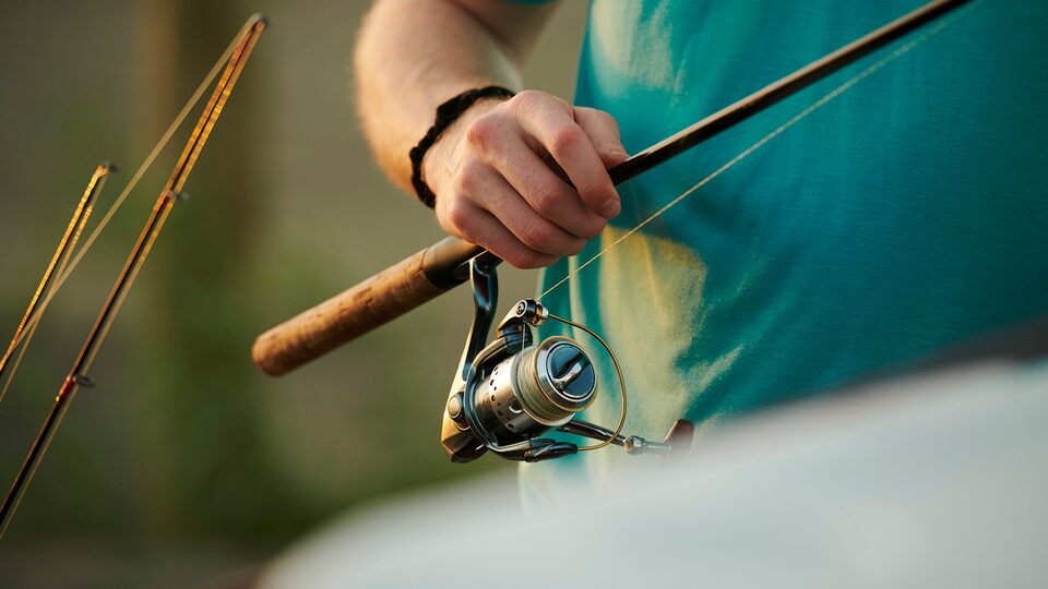 A close-up of a man’s hand holding a fishing pole.