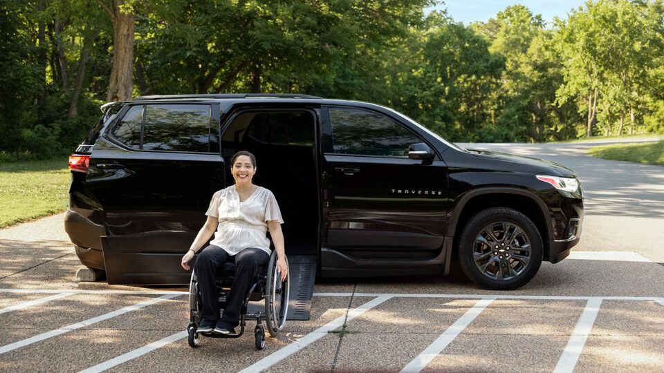 Joanna Bonilla uses a wheelchair to exit a black Chevy Traverse on a ramp.
