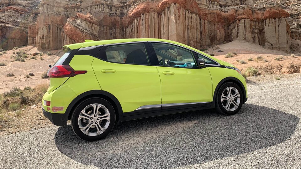 A photo of Nicole Dome’s Shock green Bolt EV on a gravel road among red rock outcroppings.