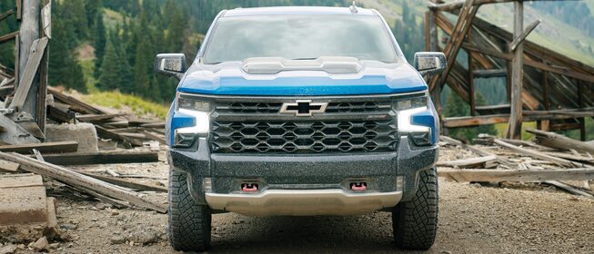 Una Silverado ZR2 azul, vista directamente de frente, con montañas y un pueblo fantasma al fondo.