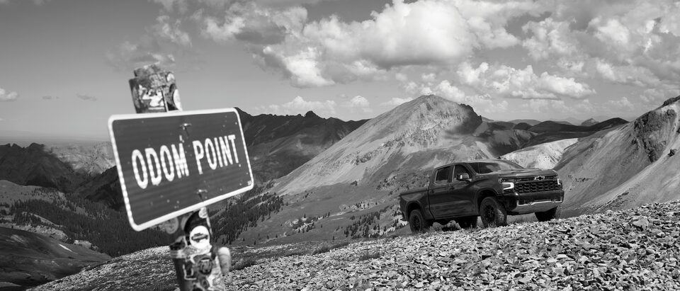 Una Silverado ZR2 en un camino de grava por encima de la línea de los árboles en las montañas de Colorado. Un letrero que reza “Odom Point” se muestra a un lado.
