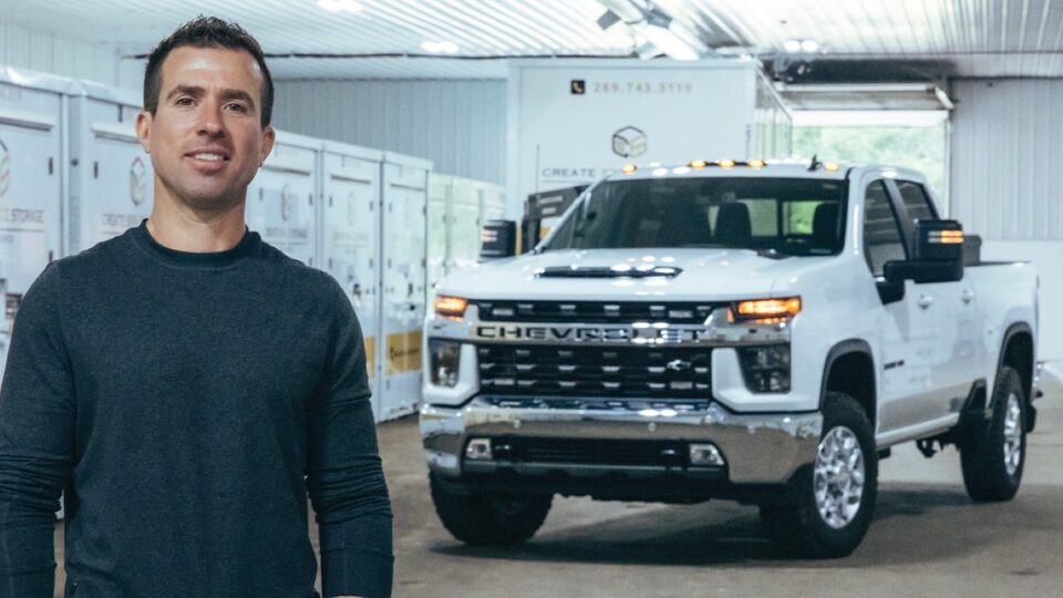 Patrick Carl está parado delante de su pickup Silverado 3500 HD en Blanco, en el interior de su depósito de almacenamiento.