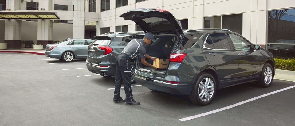  A delivery man places an Amazon package inside a Chevrolet Equinox.