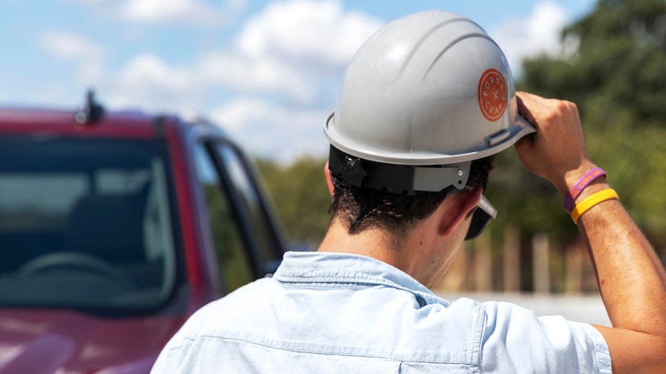 A rear shot of Jon Hagar as he removes his construction hard hat. Part of the cabin of the Chevrolet Silverado is visible in the background.