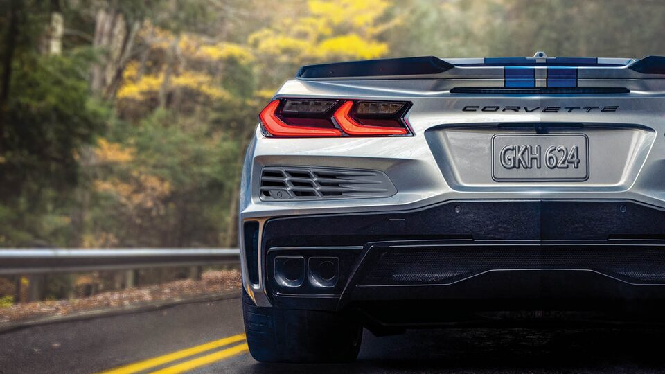 The back of a gray Corvette E-Ray with blue racing stripes.