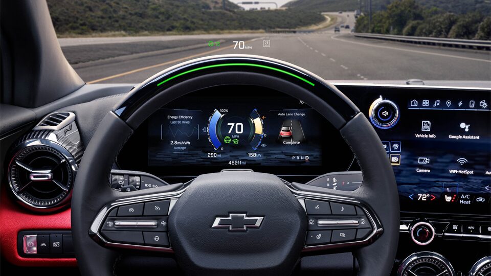 Vista hacia afuera desde el parabrisas delantero de una Blazer EV, desde la perspectiva del conductor, en la que se muestran el volante y el tablero de indicadores detrás de él.