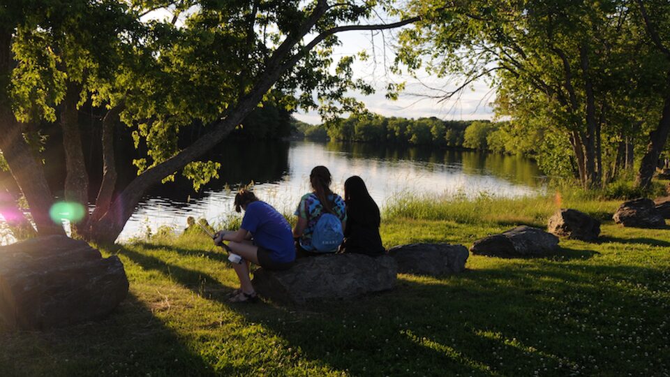 Students from the University of Maine Stormwater Management and Research Team sit near a pond.