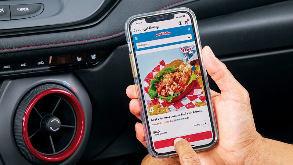 En el asiento del pasajero de la Chevy Blazer, alguien sostiene un smartphone con la aplicación de comida de Goldbelly abierta.