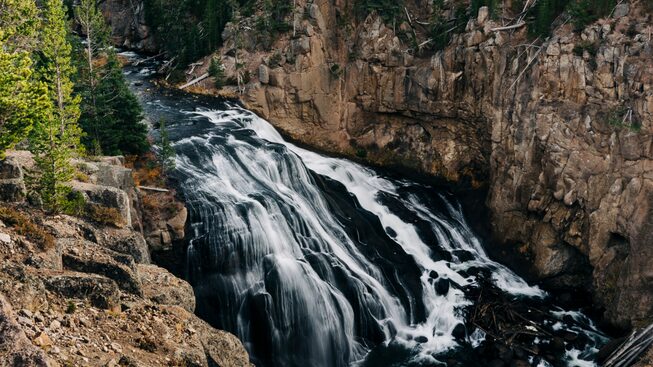 A cascade of water streams over rocks in Yellowstone.