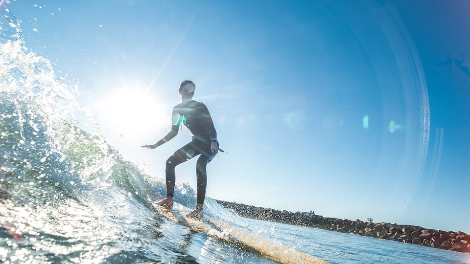 A man in a wetsuit surfs across a wave.