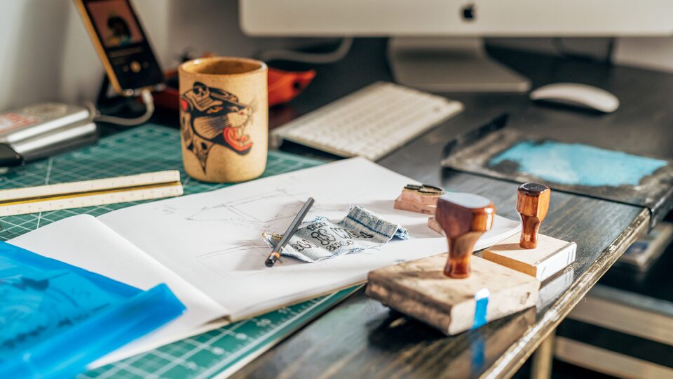 A work table with a coffee cup  and various implements on top.